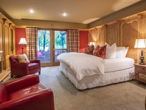 Wood paneled room with a large plush bed, outdoor patio, and fireplace.