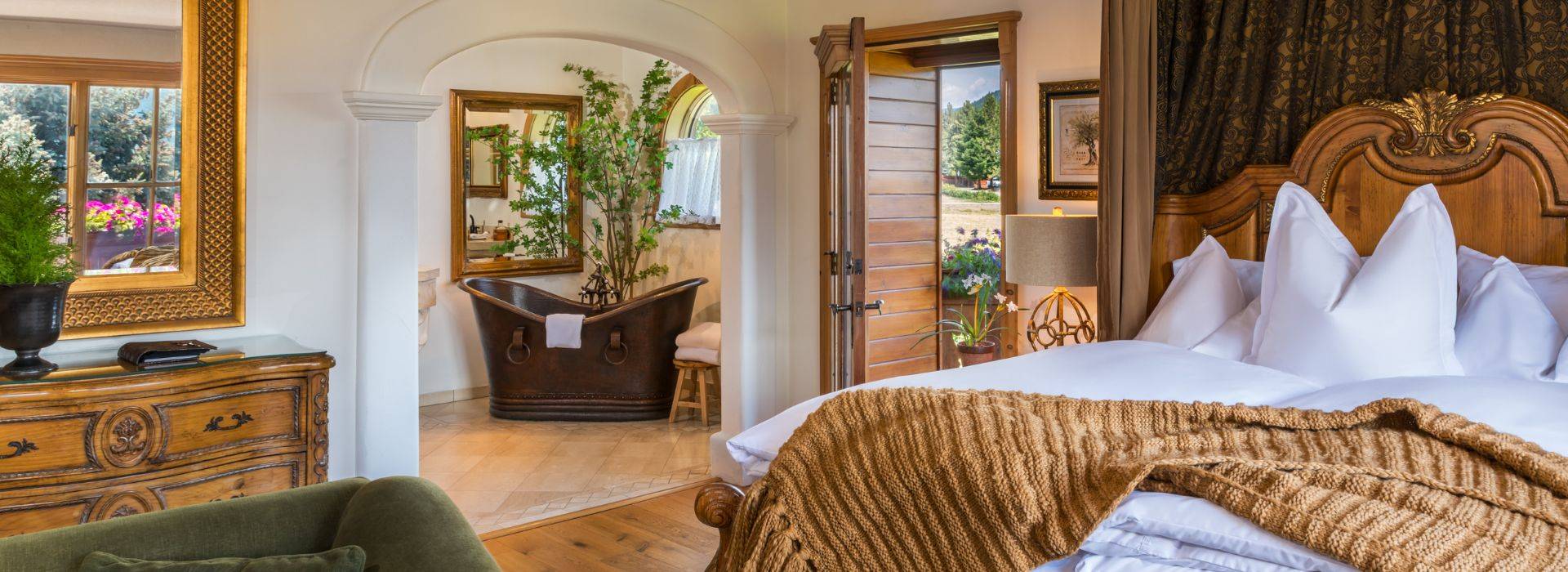 Luxurious living room with leather couch, sitting chairs in front of fireplace, piano by large windows and patio doors